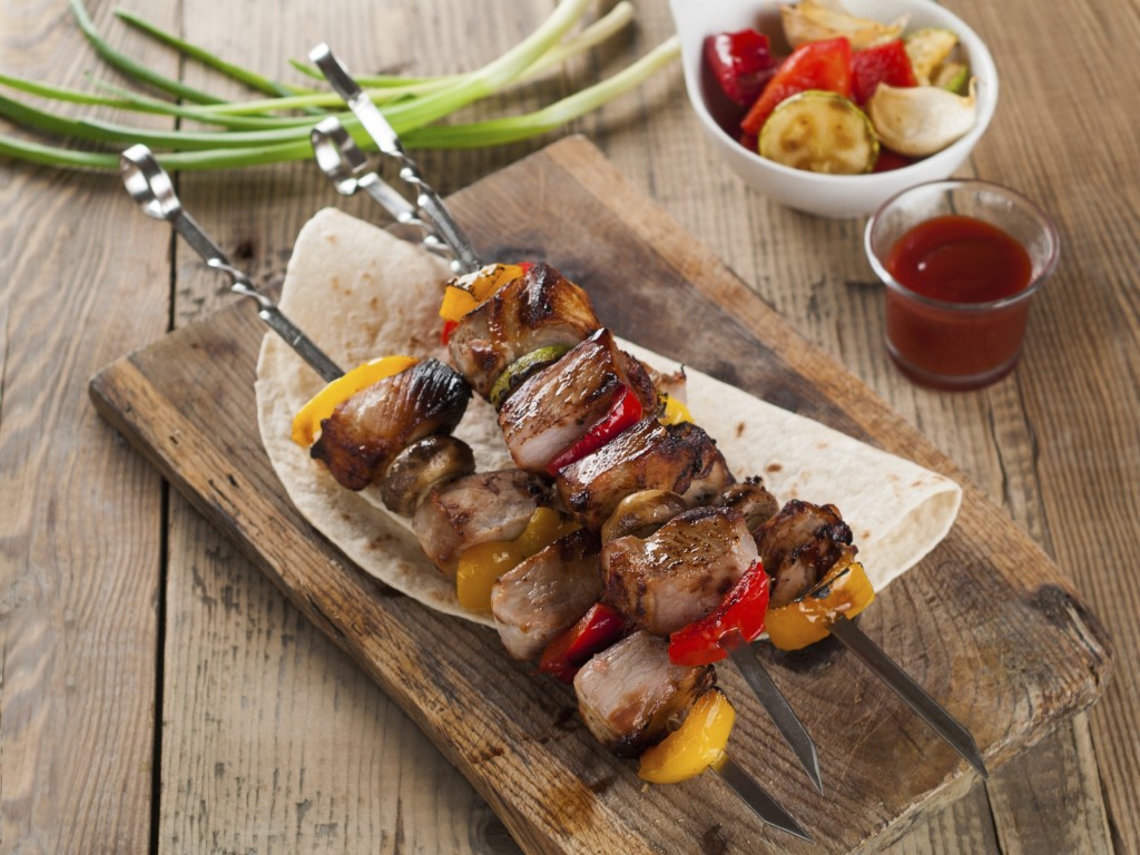Grilled meat and vegetable kebabs with sauce, selective focus