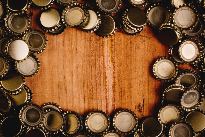 Beer bottle caps frame over wooden background