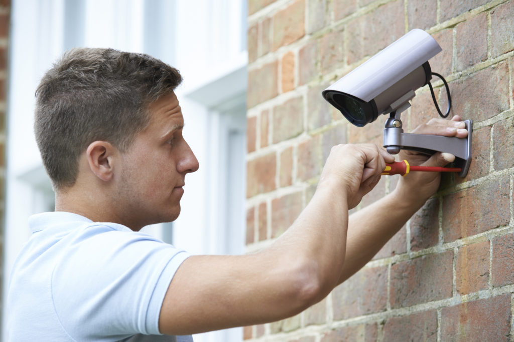 Security Consultant Fitting Security Camera To Building Wall