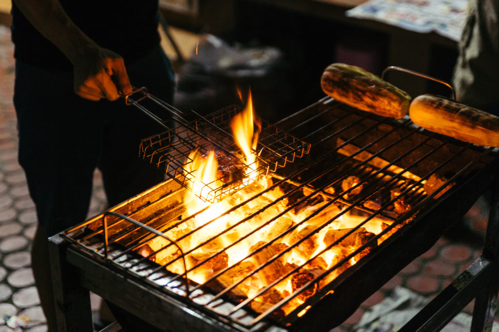 Sausages grill with burning charcoal with fire on the stove with grill on top in Bangkok, Thailand.