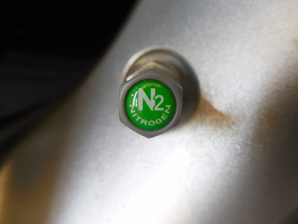 A gray plastic TPMS-safe nitrogen valve cap on an alluminum stem/alloy wheel