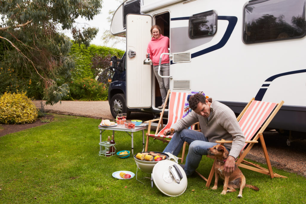 Couple In Van Enjoying Barbeque On Camping Holiday