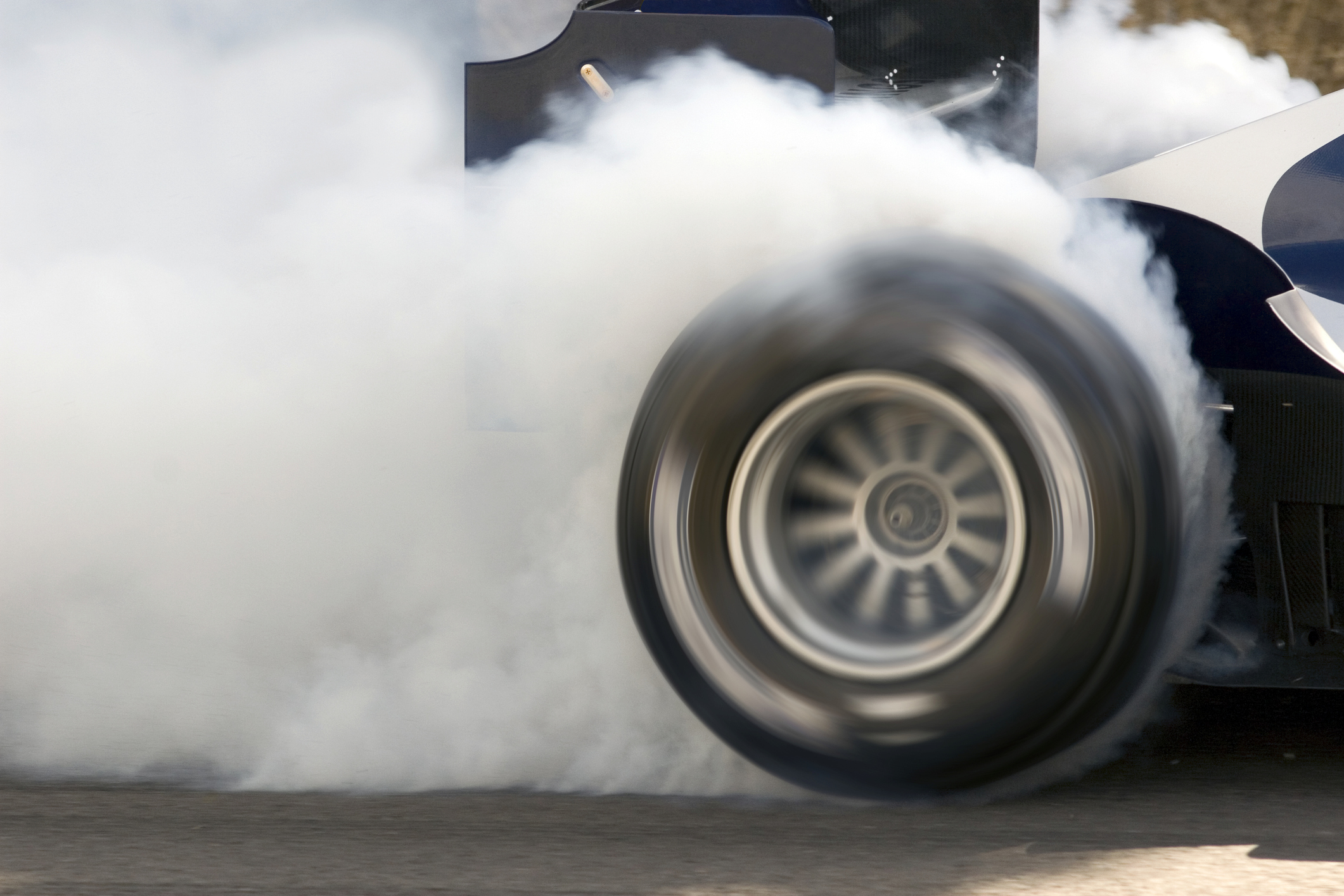 2006 Formula One Grand Prix car smoking its super slick tires. The Formula One Grand Prix car is engulfed in white smoke.