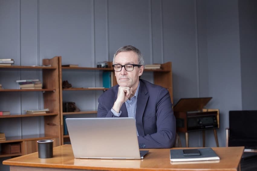 A person sitting at a desk with his hand on his chin