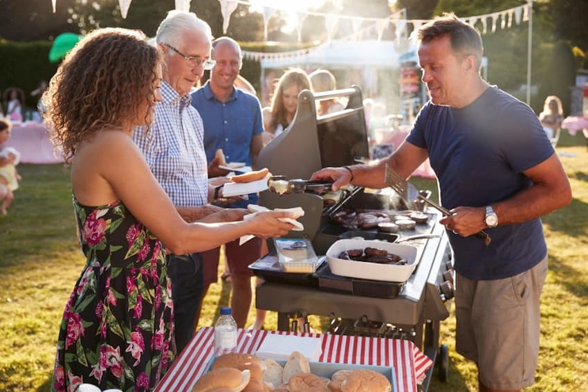 A group of people standing around a barbecue