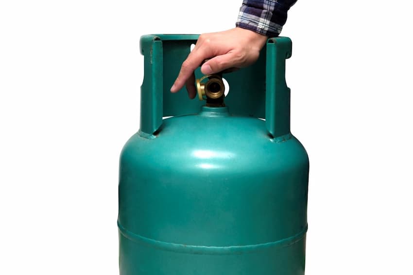 A hand holding a propane tank