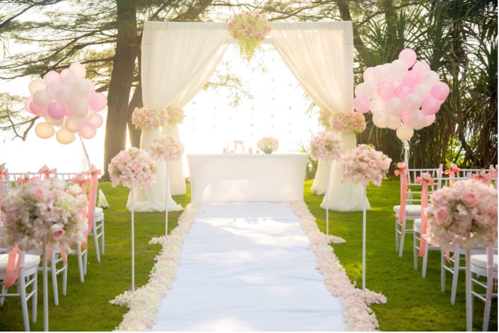A wedding ceremony with white chairs and pink balloons