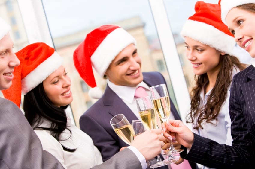 Image of cheering friends in Santa caps making toast at corporate party