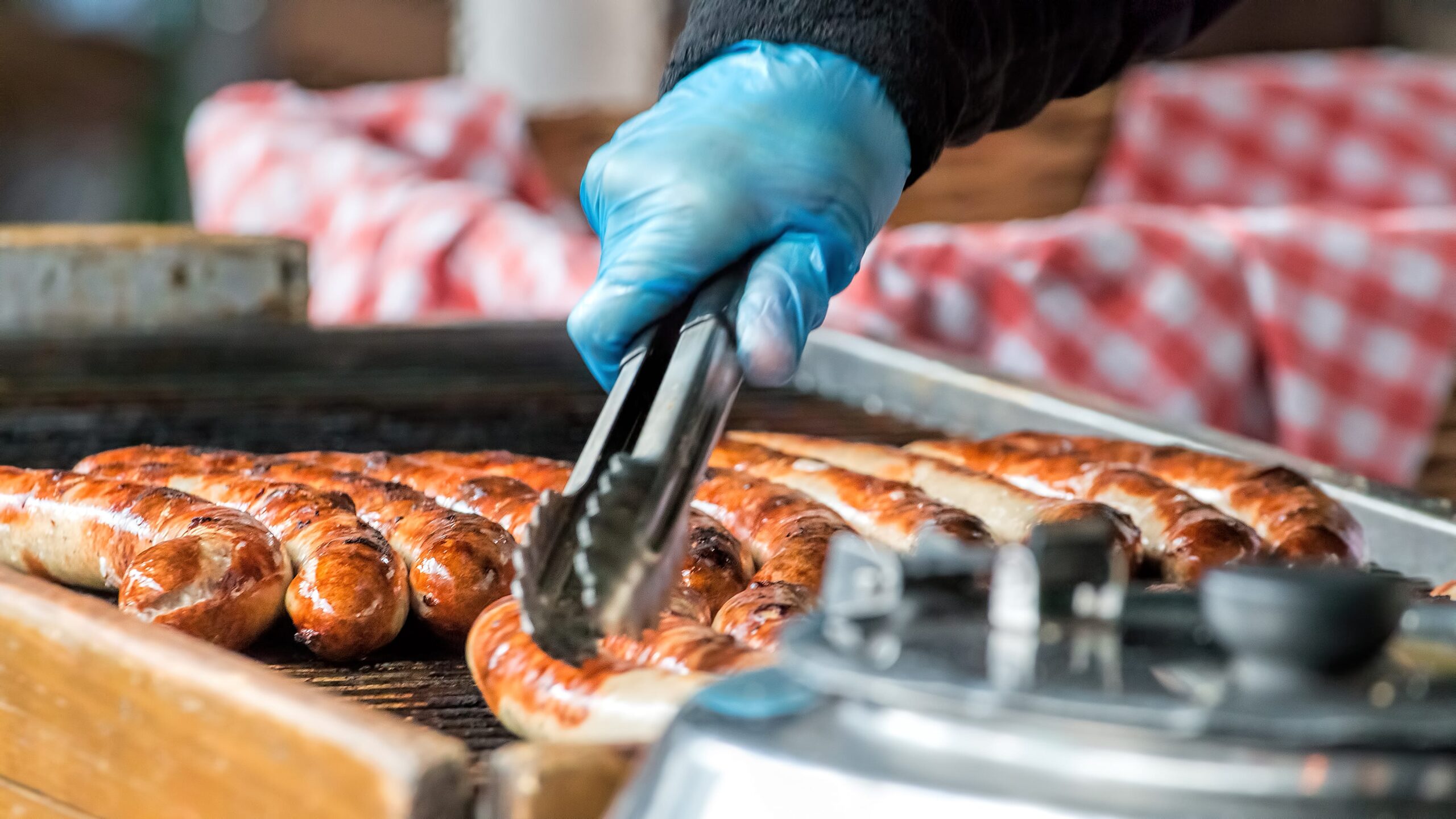 Take away sausaged being grilled at public food market stand.