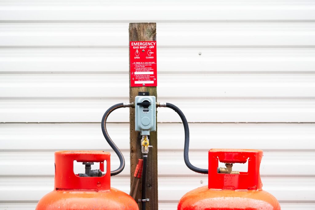 Calor gas cylinder bottles refilling with hose at refill point within caravan park site uk