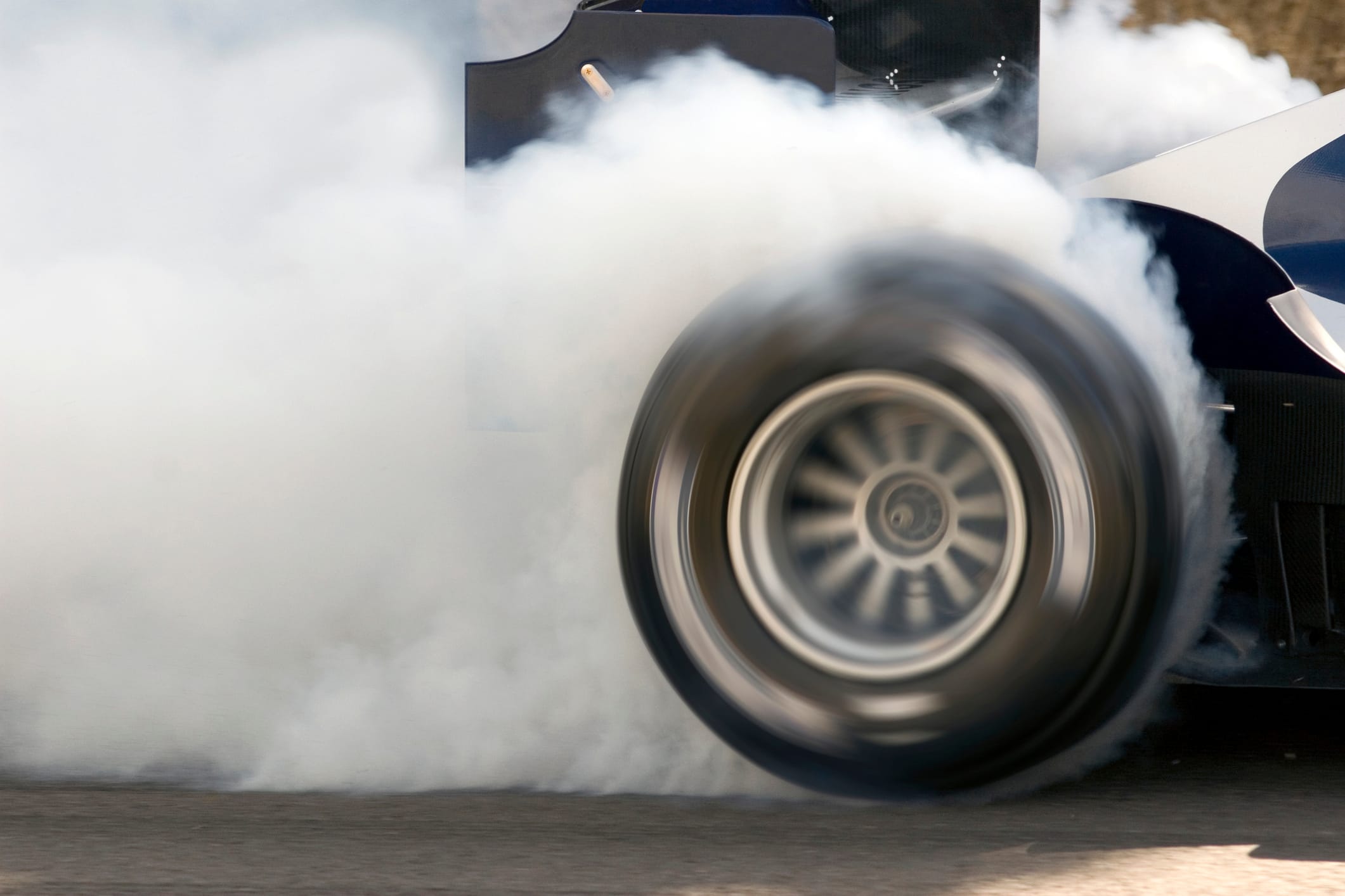 2006 Formula One Grand Prix car smoking its super slick tires. The Formula One Grand Prix car is engulfed in white smoke.