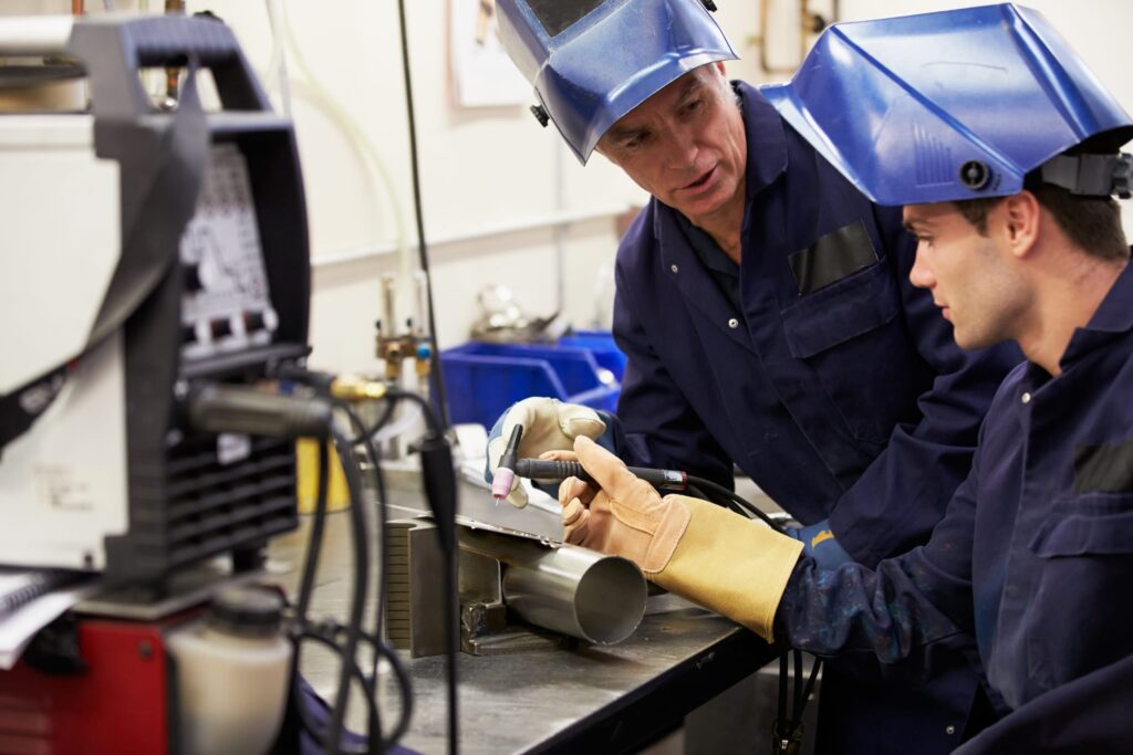 Engineer Teaching Apprentice To Use TIG Welding Machine At Work